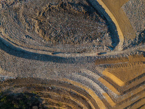 Aerial view of TPA Suwung landfill with large mounds of waste dirt access roads and heavy machinery in Kecamatan Denpasar Selatan Bali Indonesia.