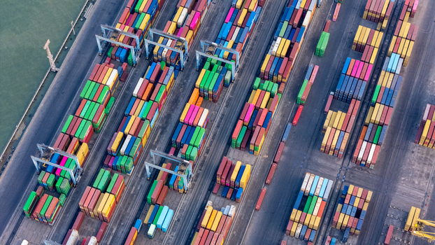 Aerial view of a busy container terminal in a port with rows of colorful shipping containers gantry cranes and paved loading areas in Semarang Central Java Indonesia. Aerial view of a busy container terminal in a port with rows of colorful shipping containers gantry cranes and paved loading areas in Semarang Central Java Indonesia.