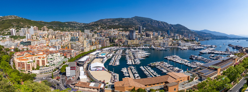 View of the bustling Port Hercules harbor filled with luxury yachts surrounded by the dense urban architecture and hills of Monaco City Monaco. View of the bustling Port Hercules harbor filled with luxury yachts surrounded by the dense urban architecture and hills of Monaco City Monaco.