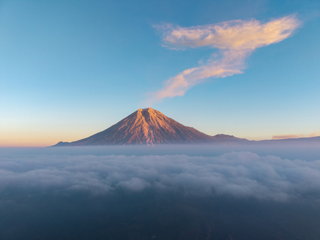 Aerial view of Semeru volcano rising above a thick layer of clouds during golden hour with soft light on the peak in Pasrujambe East Java Indonesia. Aerial view of Semeru volcano rising above a thick layer of clouds during golden hour with soft light on the peak in Pasrujambe East Java Indonesia.