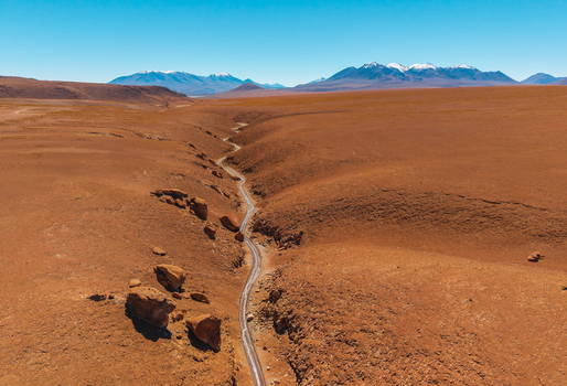 Aerial view of Canon de las Vizcachas featuring a winding road through the arid desert landscape with rocky formations and snow capped mountains in Nor Lipez Potosi Bolivia.