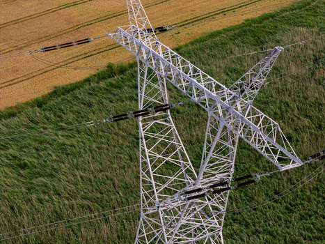 Aerial view of a high voltage power line pylon standing amidst green fields and golden crops in Gdansk Pomeranian Voivodeship Poland. Aerial view of a high voltage power line pylon standing amidst green fields and golden crops in Gdansk Pomeranian Voivodeship Poland.