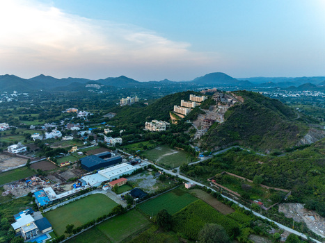 Aerial view of the hilly landscape of Udaipur with residential buildings lush green fields and distant mountains in Udaipur Rajasthan India.