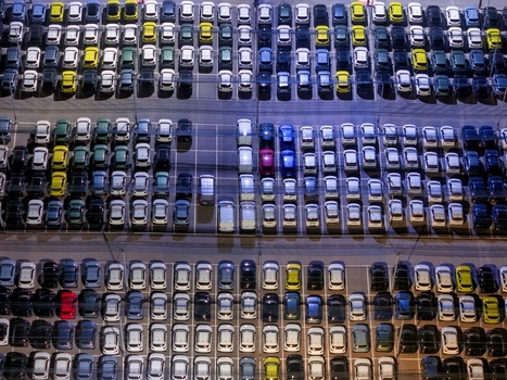 Aerial view of new cars parked at a distribution centre in rows under artificial lighting at night in Rivalta di Torino Piedmont Italy.