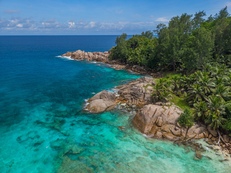 Aerial view of the vibrant turquoise waters meet the rugged rocky shoreline embraced by dense green vegetation Police Bay Mahe Island Seychelles. Aerial view of the vibrant turquoise waters meet the rugged rocky shoreline embraced by dense green vegetation Police Bay Mahe Island Seychelles.