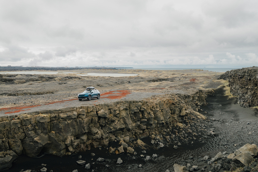 Aerial view of a car with a roof box parked on the rugged volcanic terrain near the Sandfellshaed Viewpoint in Keflavik Reykjanesbaer Iceland.