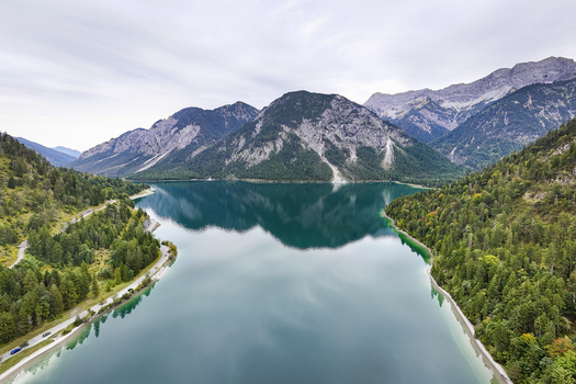 Aerial view of the serene Plansee lake mirroring the majestic Alps nestled between verdant forests under a soft sky Plansee Tyrol Austria. Aerial view of the serene Plansee lake mirroring the majestic Alps nestled between verdant forests under a soft sky Plansee Tyrol Austria.