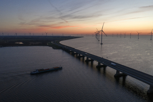 Aerial view of the Ketelbrug bridge and wind turbines at sunset with a barge on the water Nagele Flevoland Netherlands.