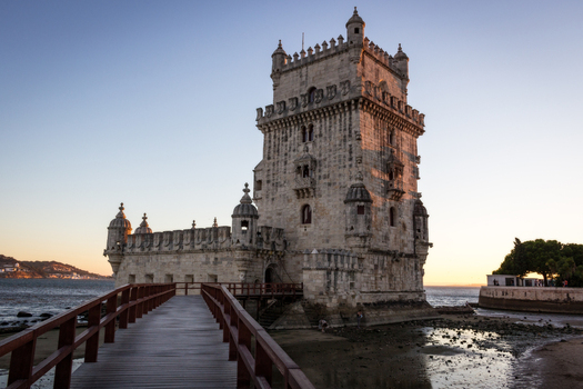 View of the historic Belem Tower with its ornate Manueline architecture and a wooden walkway over the Tagus River at sunset in Lisbon Lisbon Portugal. View of the historic Belem Tower with its ornate Manueline architecture and a wooden walkway over the Tagus River at sunset in Lisbon Lisbon Portugal.
