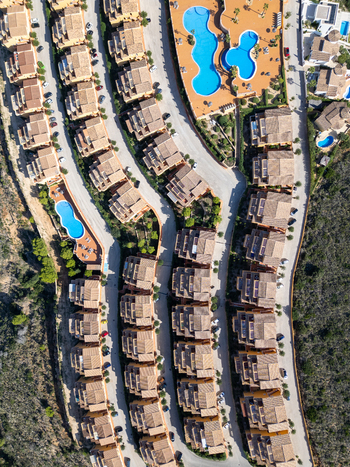 Aerial view of a residential complex with terracotta roofed houses winding roads and swimming pools in Moraira Valencian Community Spain.