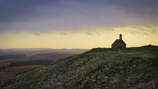 Aerial view of Mont Saint Michel de Brasparts chapel on a rocky hilltop overlooking the rolling moorland of the Monts d Arree under a dramatic cloudy sky Saint Rivoal Bretagne France. Aerial view of Mont Saint Michel de Brasparts chapel on a rocky hilltop overlooking the rolling moorland of the Monts d Arree under a dramatic cloudy sky Saint Rivoal Bretagne France.