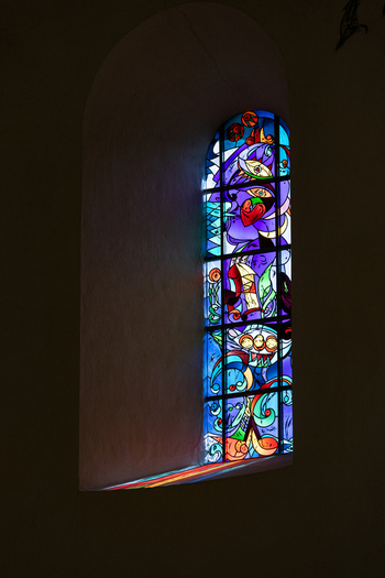 View of the modern stained glass window inside Ribe Cathedral with colorful light reflecting on the stone sill in Ribe Denmark. View of the modern stained glass window inside Ribe Cathedral with colorful light reflecting on the stone sill in Ribe Denmark.