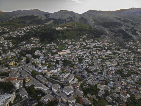 Aerial view of the historic stone city of Gjirokaster with its traditional slate roofed houses nestled against the mountains in Gjirokaster Gjirokaster County Albania. Aerial view of the historic stone city of Gjirokaster with its traditional slate roofed houses nestled against the mountains in Gjirokaster Gjirokaster County Albania.