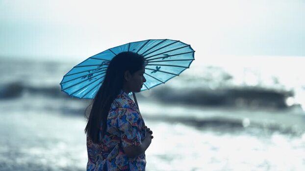 View of a woman with a blue umbrella on the beach Bangladesh. View of a woman with a blue umbrella on the beach Bangladesh.
