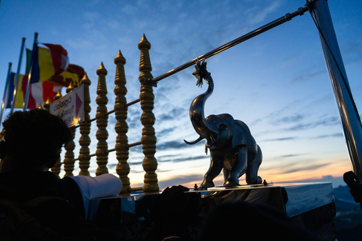 View of the silver elephant statue and colorful Buddhist flags at the summit of Adam s Peak during dawn in Ratnapura Sabaragamuwa Province Sri Lanka. View of the silver elephant statue and colorful Buddhist flags at the summit of Adam s Peak during dawn in Ratnapura Sabaragamuwa Province Sri Lanka.