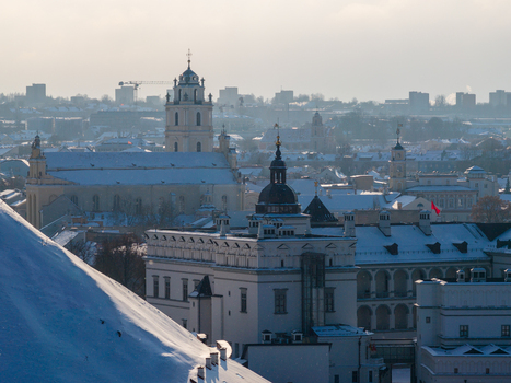 Aerial view of the snow covered Old Town with the Church of St. Johns and historic architecture under a hazy winter sky in Vilnius County Lithuania.
