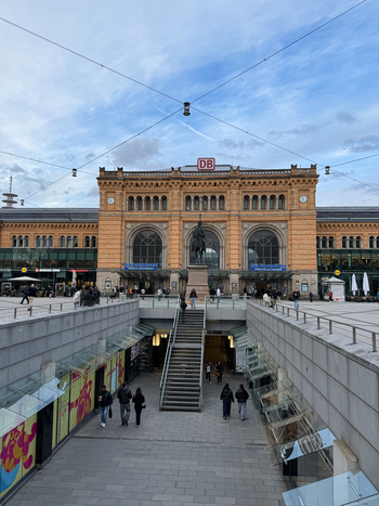 Hanover Germany 29 March 2026 View of the historic Hannover Hauptbahnhof building with the Ernst August monument in the foreground people walking on the plaza and a blue sky.