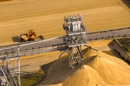Aerial view of Ashford Common Water Treatment Works with industrial conveyor structures large piles of sand and a yellow dump truck operating in Shepperton England United Kingdom. Aerial view of Ashford Common Water Treatment Works with industrial conveyor structures large piles of sand and a yellow dump truck operating in Shepperton England United Kingdom.