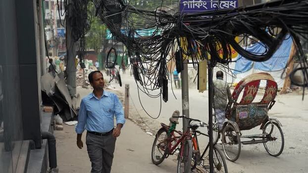 View of a man walking under tangled wires in Dhaka Bangladesh.