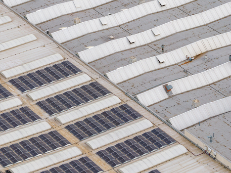 Aerial view of solar panels installed on a large industrial warehouse roof with skylights Breclav South Moravian Region Czechia.