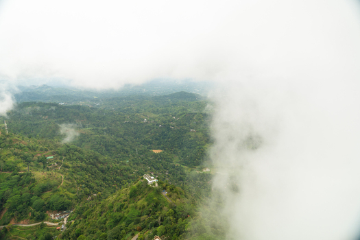 View of lush green hills and valleys partially covered by thick white clouds from Ambuluwawa Tower Gampola Central Province Sri Lanka. View of lush green hills and valleys partially covered by thick white clouds from Ambuluwawa Tower Gampola Central Province Sri Lanka.