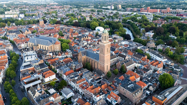 Aerial view of the historic Grote of Sint Michaelkerk surrounded by dense urban rooftops narrow streets and lush green trees in the city center of Zwolle Overijssel Netherlands.