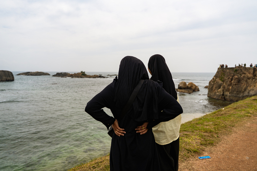 Sri Lanka 07 January 2026 View of two women in traditional Muslim attire looking at the Indian Ocean from the historic ramparts of Galle Fort.