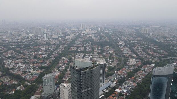 Aerial view of the dense urban landscape of Jakarta Pusat with modern skyscrapers residential rooftops and lush green trees in Kecamatan Menteng Daerah Khusus Ibukota Indonesia. Aerial view of the dense urban landscape of Jakarta Pusat with modern skyscrapers residential rooftops and lush green trees in Kecamatan Menteng Daerah Khusus Ibukota Indonesia.