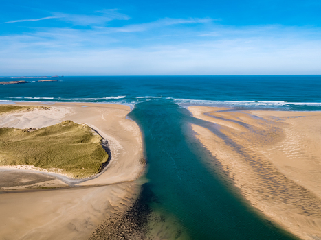 Aerial view of Ballyness Bay featuring expansive sandy beaches grassy dunes and a deep blue tidal channel flowing into the Atlantic Ocean in Ballyness County Donegal Ireland. Aerial view of Ballyness Bay featuring expansive sandy beaches grassy dunes and a deep blue tidal channel flowing into the Atlantic Ocean in Ballyness County Donegal Ireland.