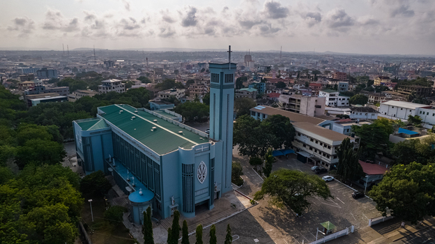 Aerial view of Holy Spirit Cathedral with its distinctive blue facade and tall bell tower surrounded by urban buildings and lush trees in Accra Greater Accra Region Ghana. Aerial view of Holy Spirit Cathedral with its distinctive blue facade and tall bell tower surrounded by urban buildings and lush trees in Accra Greater Accra Region Ghana.
