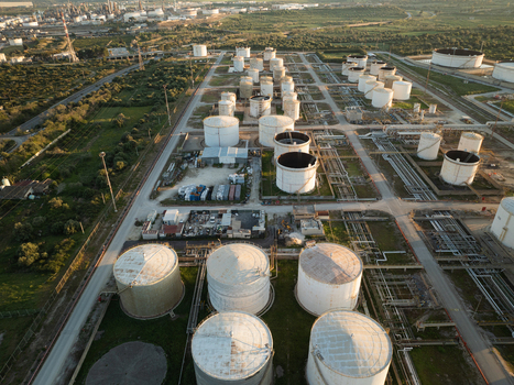 Aerial view of an industrial oil refinery with large white storage tanks and complex piping systems Augusta Sicily Italy. Aerial view of an industrial oil refinery with large white storage tanks and complex piping systems Augusta Sicily Italy.