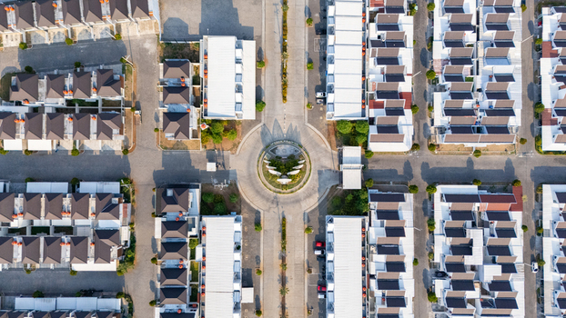 Aerial view of a modern residential complex featuring uniform houses with dark roofs arranged around a central roundabout in a planned neighborhood in Semarang Central Java Indonesia. Aerial view of a modern residential complex featuring uniform houses with dark roofs arranged around a central roundabout in a planned neighborhood in Semarang Central Java Indonesia.