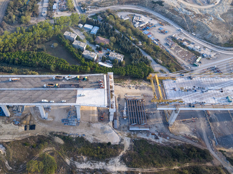 Aerial view of a bridge under construction with heavy machinery and vehicles on the deck surrounded by trees and roads in Istanbul Istanbul Turkiye.