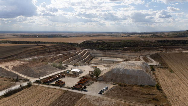 Aerial view of the Besenovo quarry with heavy machinery and dump trucks parked in the yard surrounded by agricultural fields in Besenovo Vojvodina Serbia. Aerial view of the Besenovo quarry with heavy machinery and dump trucks parked in the yard surrounded by agricultural fields in Besenovo Vojvodina Serbia.