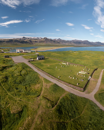 Aerial view of the historic black wooden church Budakirkja surrounded by a grassy cemetery coastal landscape and distant mountains in Budir Snaefellsbaer Iceland. Aerial view of the historic black wooden church Budakirkja surrounded by a grassy cemetery coastal landscape and distant mountains in Budir Snaefellsbaer Iceland.