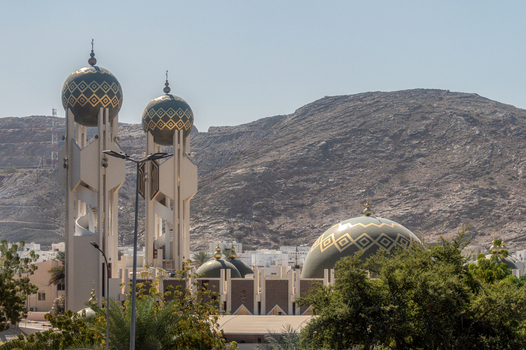 View of the Mohammed Al Ameen Mosque with its distinctive green domes and tall minarets set against a rugged mountain backdrop in Muscat Muscat Governorate Oman. View of the Mohammed Al Ameen Mosque with its distinctive green domes and tall minarets set against a rugged mountain backdrop in Muscat Muscat Governorate Oman.