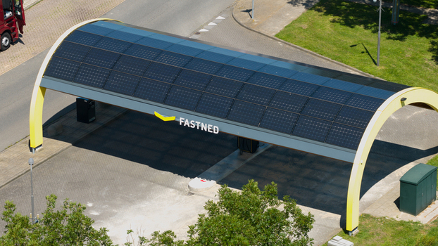 Middenbeemster Noord Holland Netherlands 20 June 2026 Aerial view of Fastned charging station with solar panel roof and yellow arch structure in a paved parking area.
