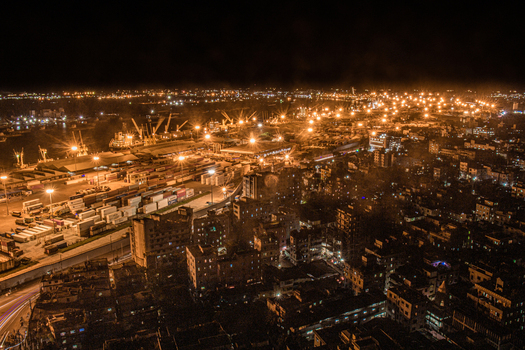 Chittagong Bangladesh 01 September 2021 Aerial view of Chattogram Port at night with illuminated shipping containers cargo ships cranes and the surrounding urban landscape.