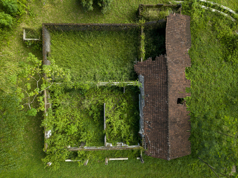 Aerial view of houses damaged by Mount Merapi eruption with a ruined tiled roof and lush vegetation growing inside the walls Cangkringan Special Region of Yogyakarta Indonesia. Aerial view of houses damaged by Mount Merapi eruption with a ruined tiled roof and lush vegetation growing inside the walls Cangkringan Special Region of Yogyakarta Indonesia.