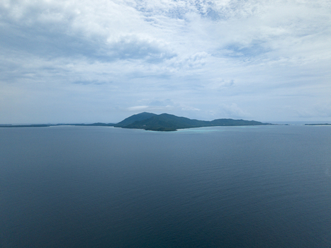 Aerial view of lush green island surrounded by deep blue waters under a serene sky Cemara Kecil Island Karimunjawa Central Java Indonesia.
