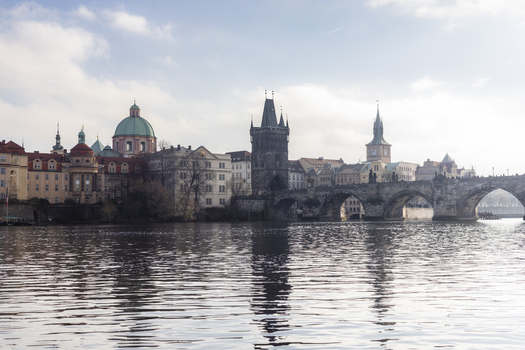 View of Charles Bridge and the Old Town Bridge Tower across the Vltava River with historic architecture and a soft cloudy sky Prague Prague Czechia. View of Charles Bridge and the Old Town Bridge Tower across the Vltava River with historic architecture and a soft cloudy sky Prague Prague Czechia.