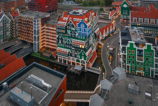 Zaandam Netherlands 26 April 2022 Aerial view of Inntel Hotels Amsterdam Zaandam with its unique stacked traditional house facade and surrounding urban canals at dusk.