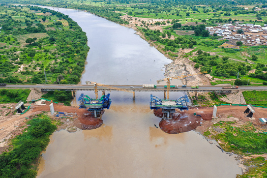 Aerial view of the construction site of the new Yapei Bridge over the White Volta River featuring heavy machinery and cranes alongside the existing bridge Yapei Savannah Region Ghana.