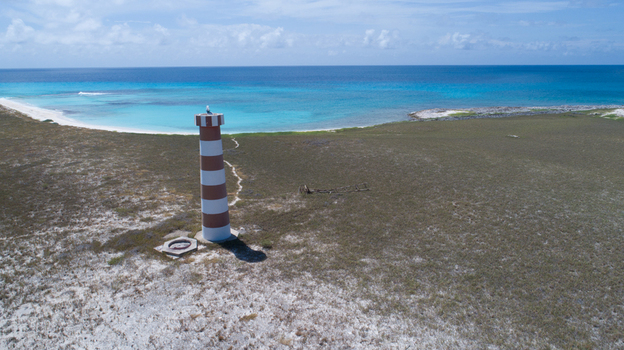 Aerial view of the striped lighthouse on the Los Roques archipelago surrounded by sandy terrain and turquoise Caribbean waters in Los Roques Dependencias Federale Venezuela. Aerial view of the striped lighthouse on the Los Roques archipelago surrounded by sandy terrain and turquoise Caribbean waters in Los Roques Dependencias Federale Venezuela.