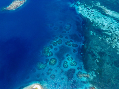 Aerial view of the vibrant coral reefs and turquoise waters surrounding the island of Guanaja Bay Islands Department Honduras. Aerial view of the vibrant coral reefs and turquoise waters surrounding the island of Guanaja Bay Islands Department Honduras.