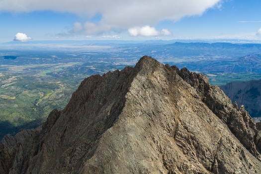 Aerial view of Mount Sneffels in the San Juan Mountains featuring rugged rocky peaks deep valleys and expansive vistas under a clear blue sky in Ouray County Colorado United States. Aerial view of Mount Sneffels in the San Juan Mountains featuring rugged rocky peaks deep valleys and expansive vistas under a clear blue sky in Ouray County Colorado United States.