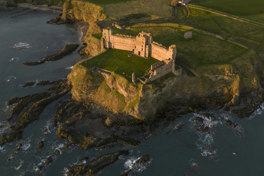 Aerial view of the ruined Tantallon Castle perched on high cliffs overlooking the North Sea during golden hour North Berwick Scotland United Kingdom.