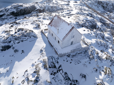 Aerial view of a snow covered building with a red roof amid a stark white landscape Lagoa Comprida São Romão Serra da Estrella Portugal. Aerial view of a snow covered building with a red roof amid a stark white landscape Lagoa Comprida São Romão Serra da Estrella Portugal.