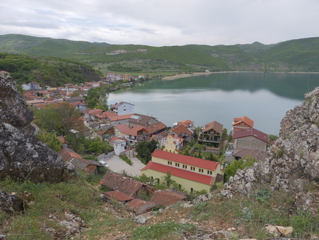View of the village of Lin with its traditional red tiled roofs and a prominent church situated on the shores of Lake Ohrid surrounded by green hills in Lin Korce County Albania.
