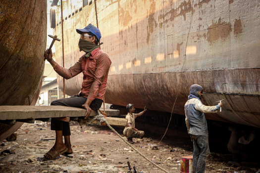Keraniganj Bangladesh 03 November 2023 View of workers repairing a large rusty ship hull with hammers at the Shipyard Dhaka.
